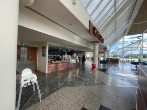 From end of path looking at venue. Wide opening ahead. Pillar on left and in far back. Path ahead to counter along back left.