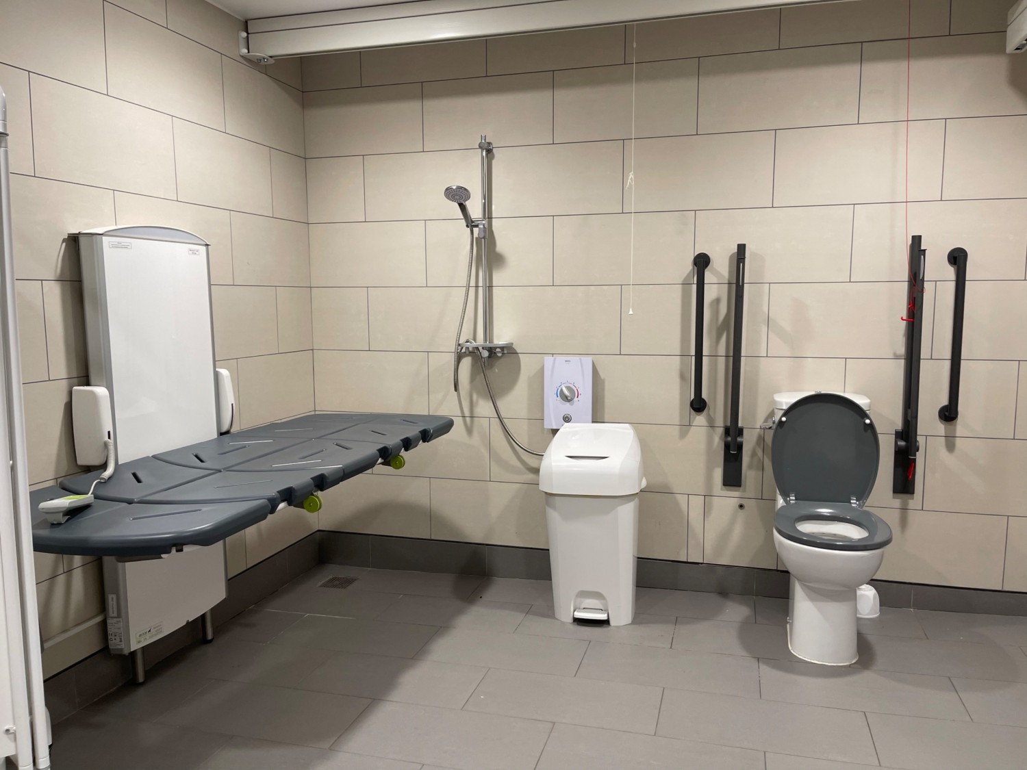 On the left we have an adult sized changing table and shower, sanitary bed and then a toilet with both left and right side transfer rails