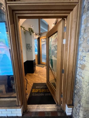 Wood framed glass door. Push open via long silver handle on left.
