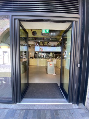Glass double door, with black doorframe. Push at centre to open.