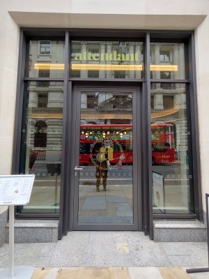 Glass door with silver metal handle to left. Push to open