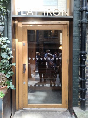 Glass door with wooden frame. Handle on left. Pull to open.