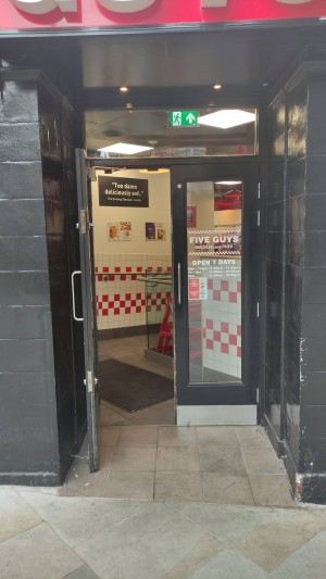 Pull glass doors with black frames ahead. Vertical door handles on centre of door. Built in ramp at foot of door.